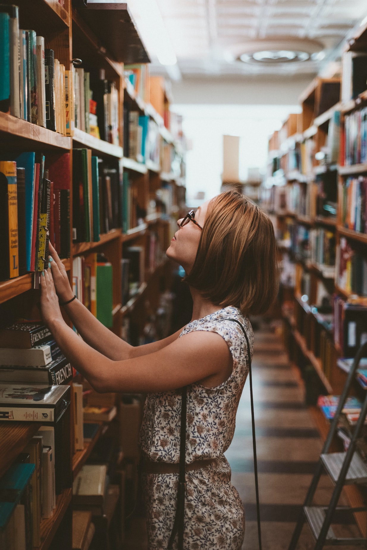 Woman Looking Through Library Shelves