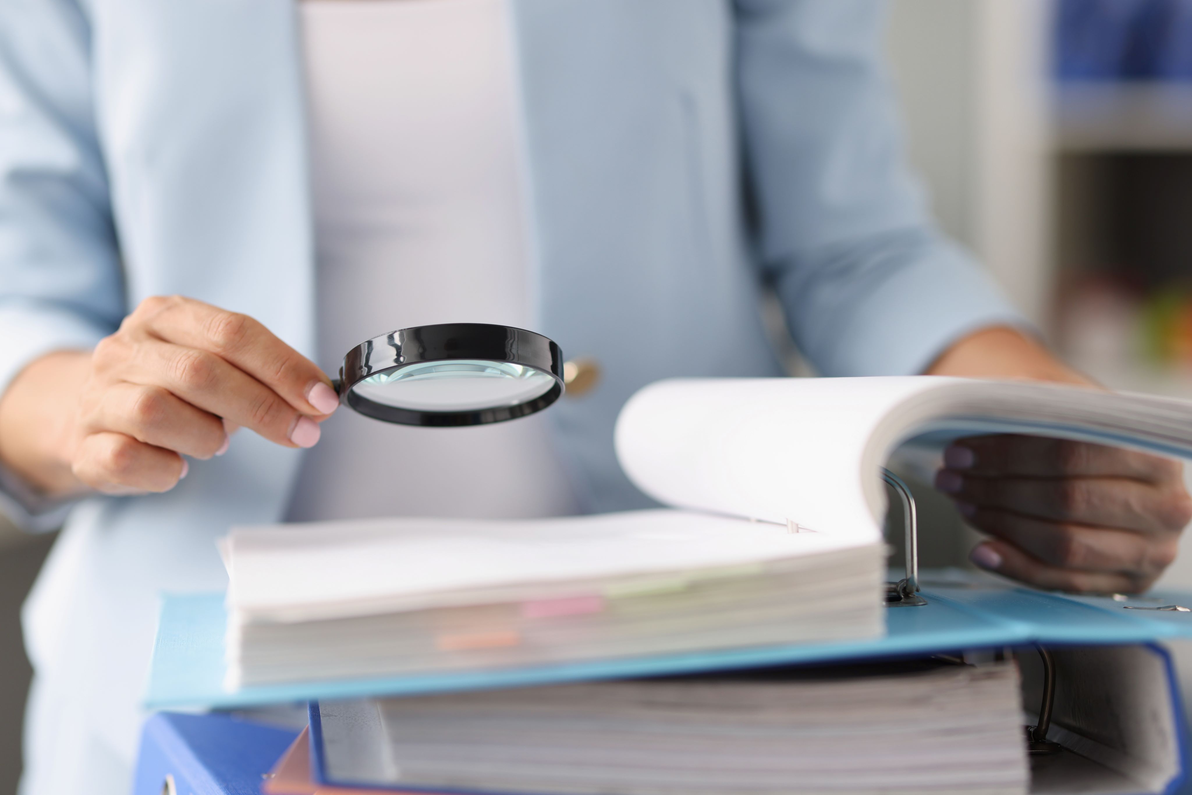 Businesswoman looking through magnifying glass tool on documents