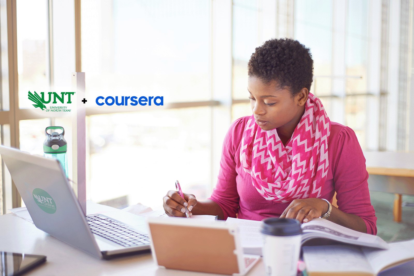 Person learning at their laptop with a notebook, and the UNT + Coursera Logo